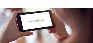 hands holding a smartphone with the Covenant Living logo on screen