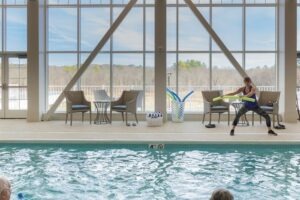 A woman instructing a swim exercise in an indoor pool