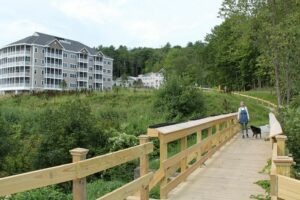 A woman walking her dog outside on a walking path near the Covenant Living of Keene building