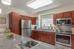 An apartment interior of a kitchen with stone countertops and wood cabinets