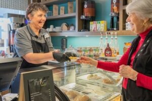 A woman smiling while getting a pastry from a cafe