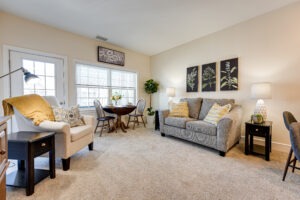 Interior of an apartment living area with a couch, loveseat and coffee table, decorated with paintings