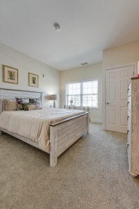 Interior of an apartment bedroom with a bed, bureau, and closet