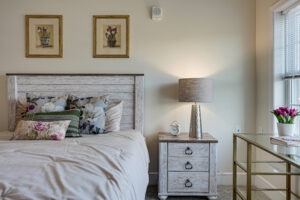 Close up interior of an apartment bedroom with bed and nightstand next to windows