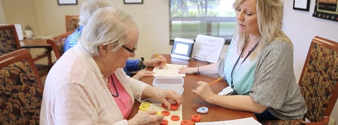 a healthcare proffessional working with two people doing memory puzzles