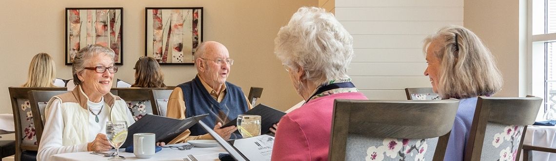 3 women and a gentleman sitting in the dining room table looking at menus