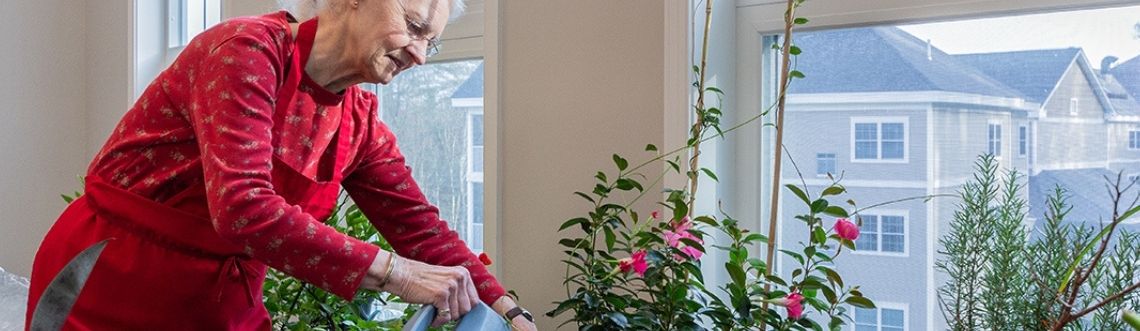 older woman smiling while watering plants